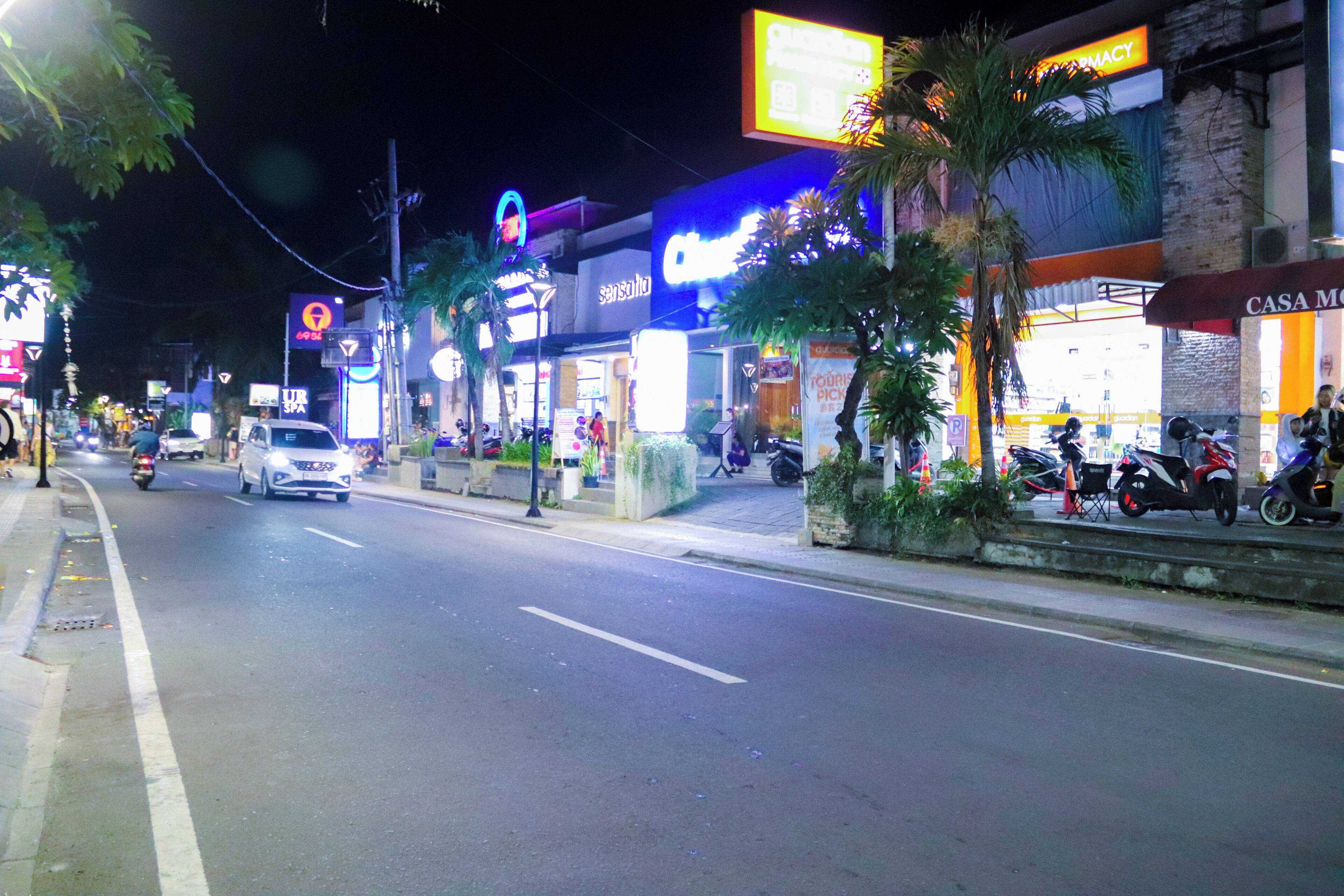 A street lined with shops and a pharmacy.