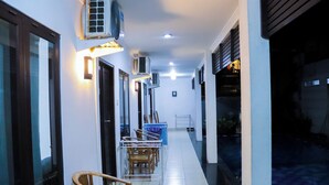 A hallway with chairs, an air conditioning unit, and a tiled floor. - Sanur Guest House (Denpasar)