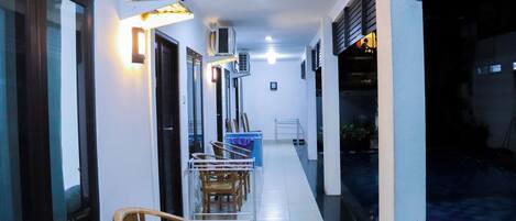 A hallway with chairs, an air conditioning unit, and a tiled floor.