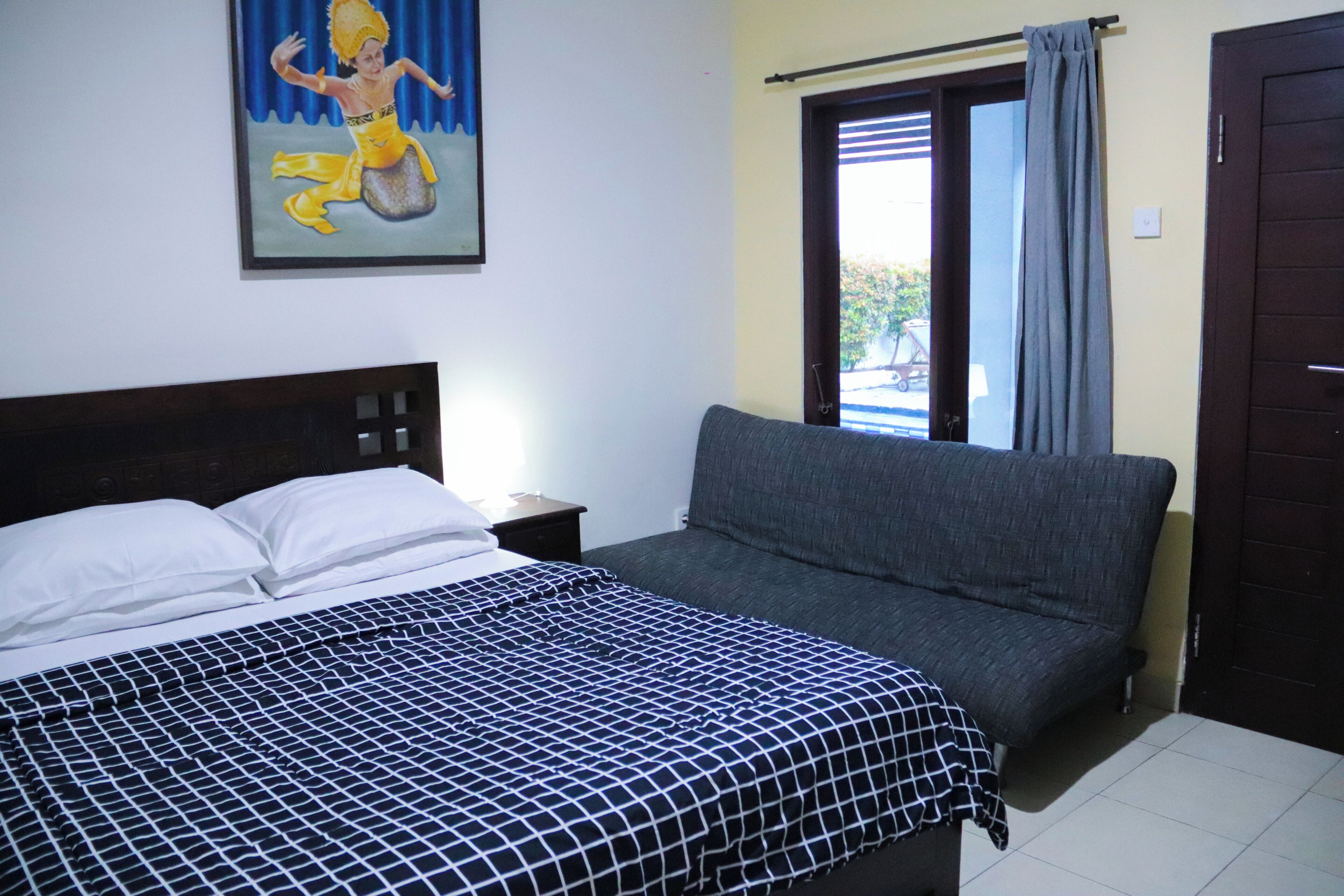A bedroom with a bed, a sofa, a window with curtains, and a door.