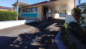 A building with a covered entrance, a brick facade, and a small garden area with plants and flowers. - Aspley Sunset Motel (Aspley)