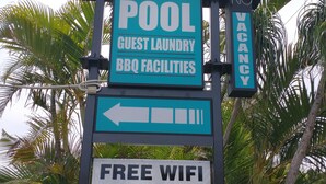 A motel sign with amenities including a pool, guest laundry, BBQ facilities, free WiFi, and 24hr CCTV. - Aspley Sunset Motel (Aspley)