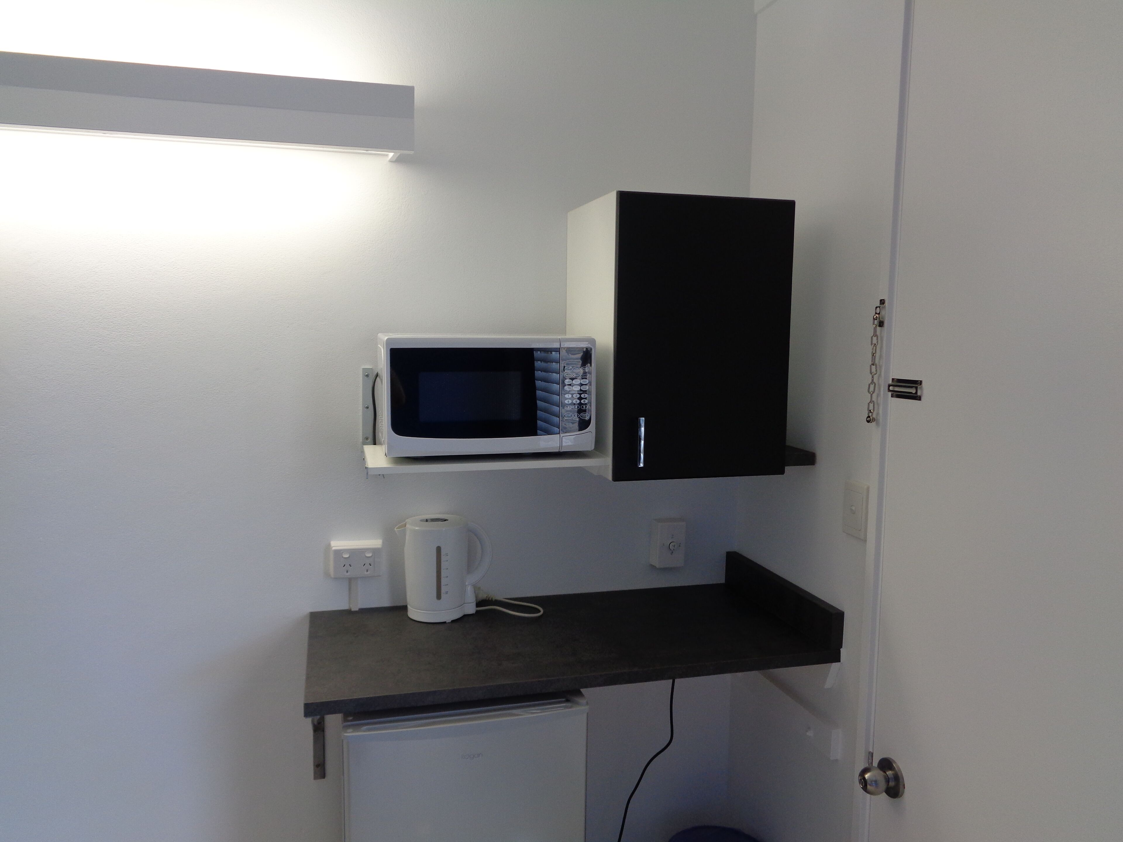 A compact kitchenette with a microwave, a coffee maker, and a small refrigerator.