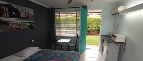 Un dormitorio con cama, escritorio, silla y ventilador de techo.