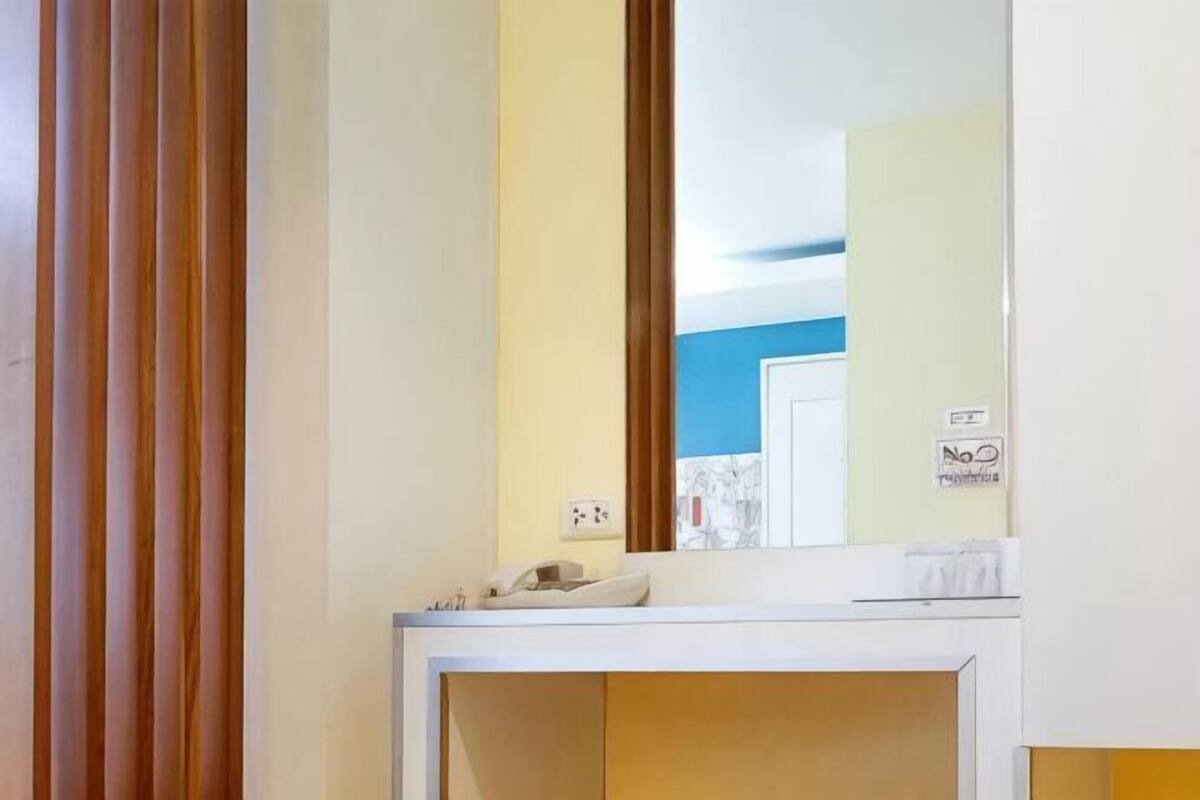 A room with a mirror, a telephone, and a door with a blue wall in the background.