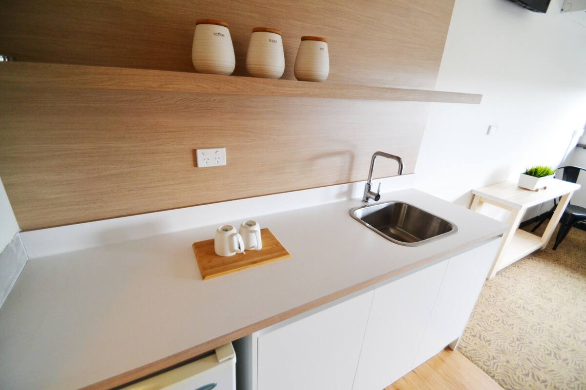 A modern kitchen with white cabinets, a stainless steel sink, and a wooden countertop.