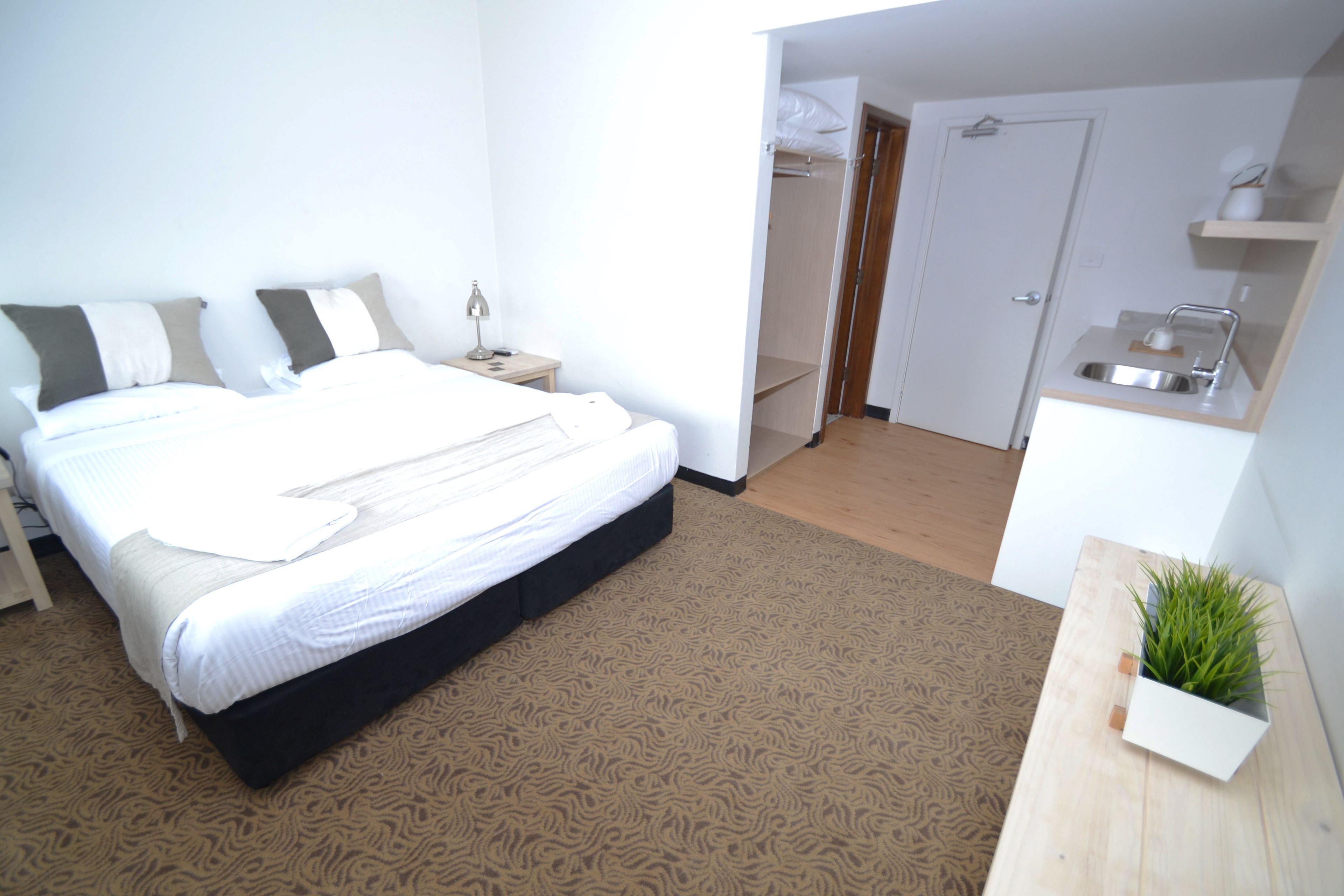 A bedroom with a bed, bedside table, and a small plant.