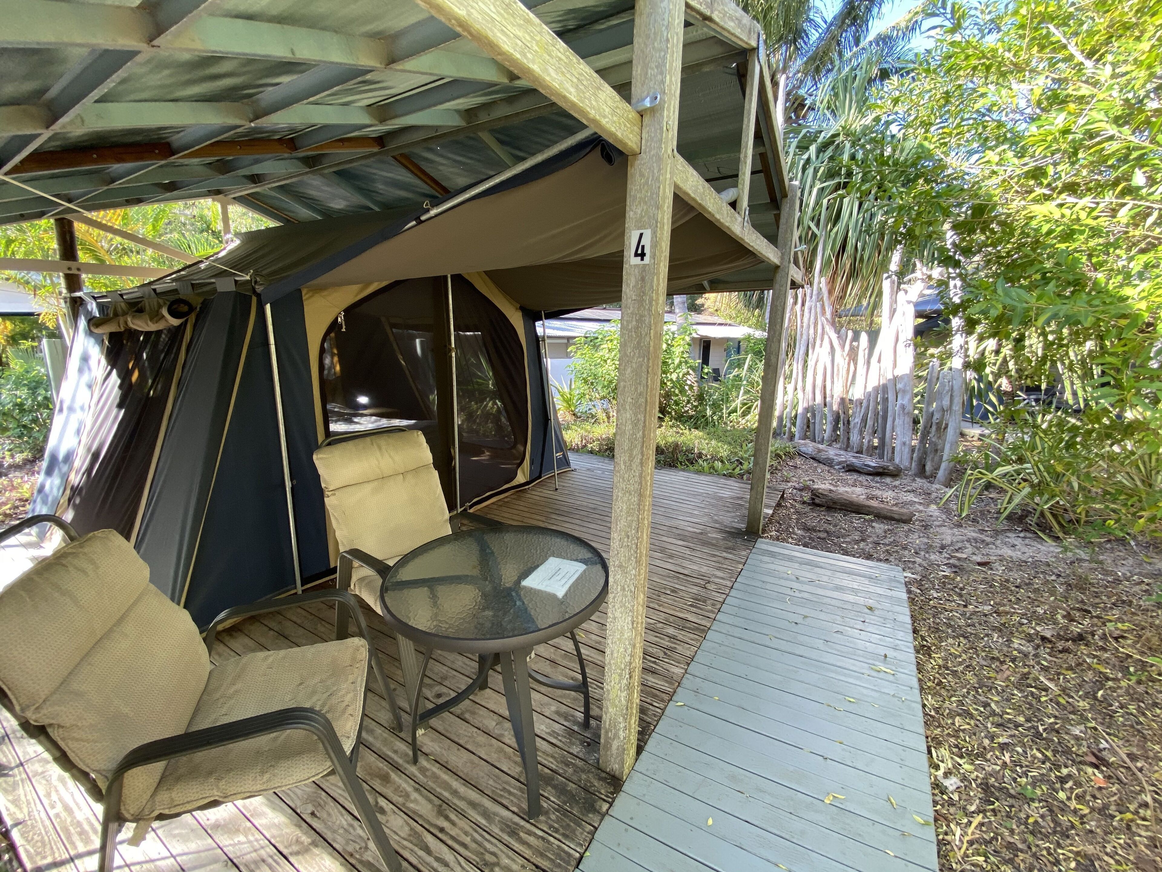 Un espacio al aire libre techado con mesa y sillas, una carpa y una terraza de madera.