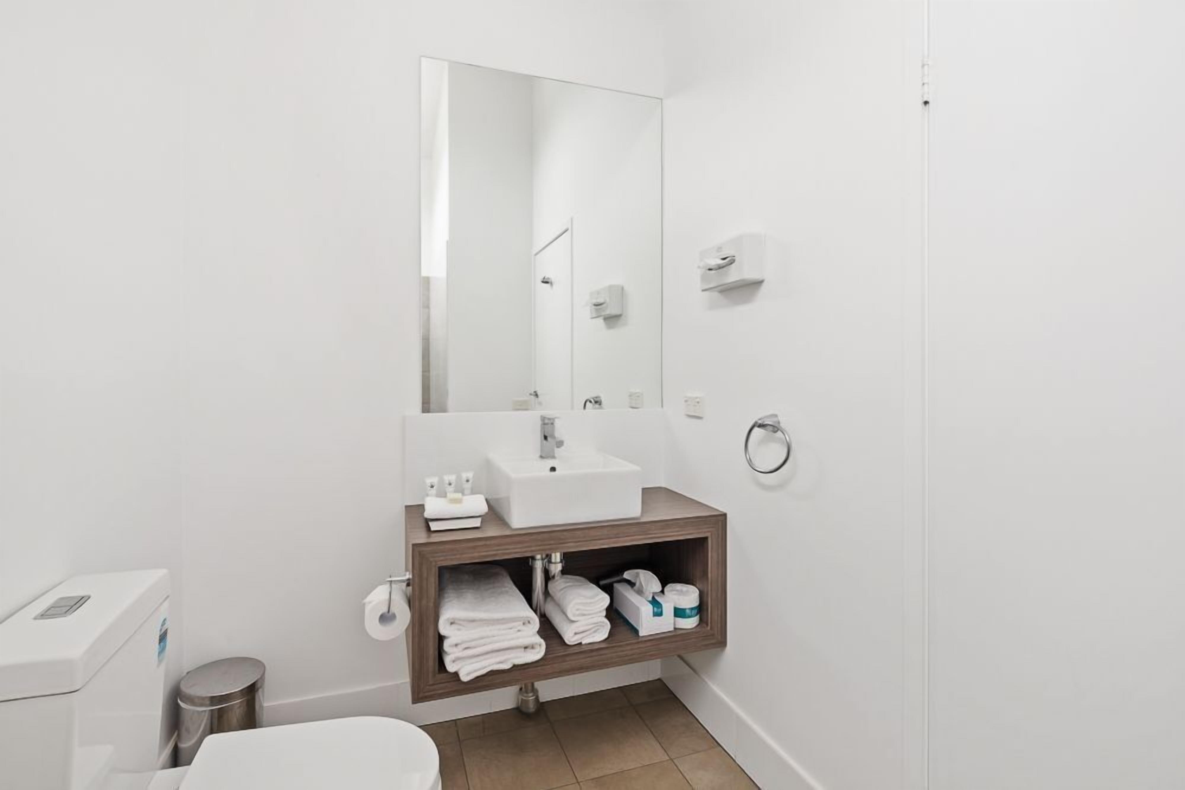A modern bathroom with a white sink, mirror, and toilet.