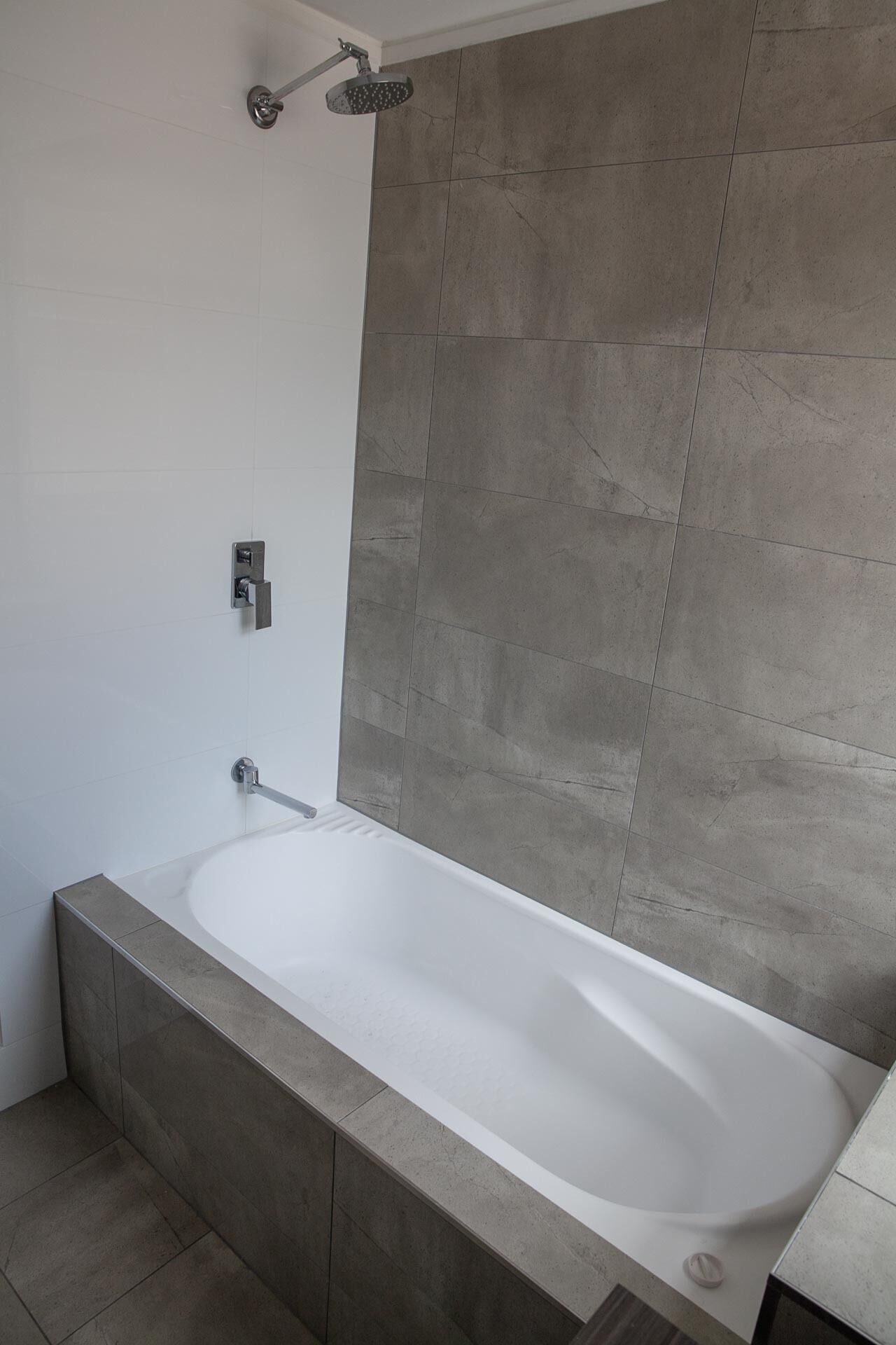 Ein modernes Badezimmer mit einer freistehenden Badewanne, einer Duschbrause und einer wandmontierten Bedienkonsole.
