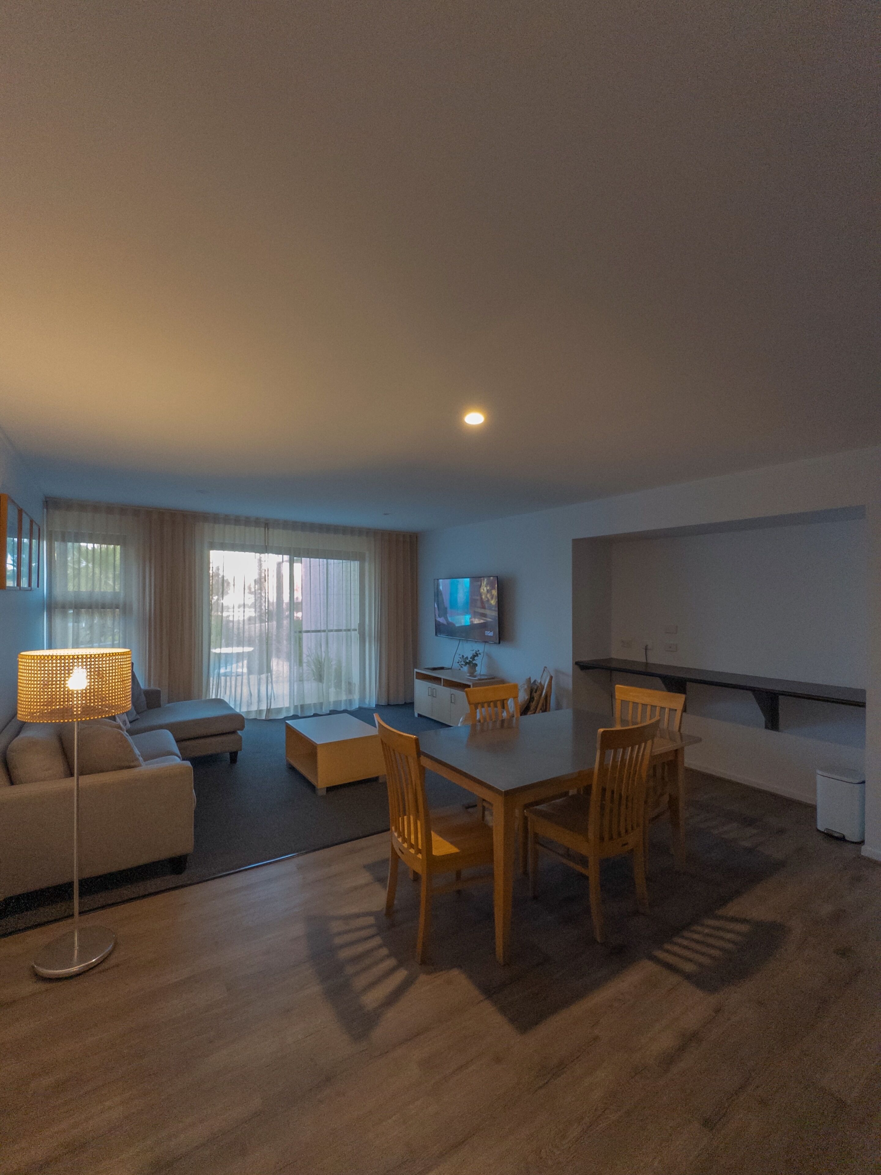 En moderne stue med spiseplads, en sofa, et fjernsyn og et stort vindue.