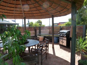 An outdoor patio with a grill, seating, and potted plants. - Mandalay Motel (Roma)