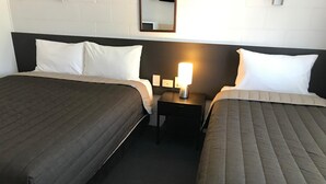 Une chambre d’hôtel avec deux lits, une table de chevet avec une lampe et un miroir au mur.
