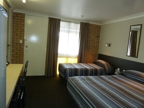 A hotel room with two beds, a desk, a chair, a window with curtains, and a mirror on the wall. - Mandalay Motel (Roma)