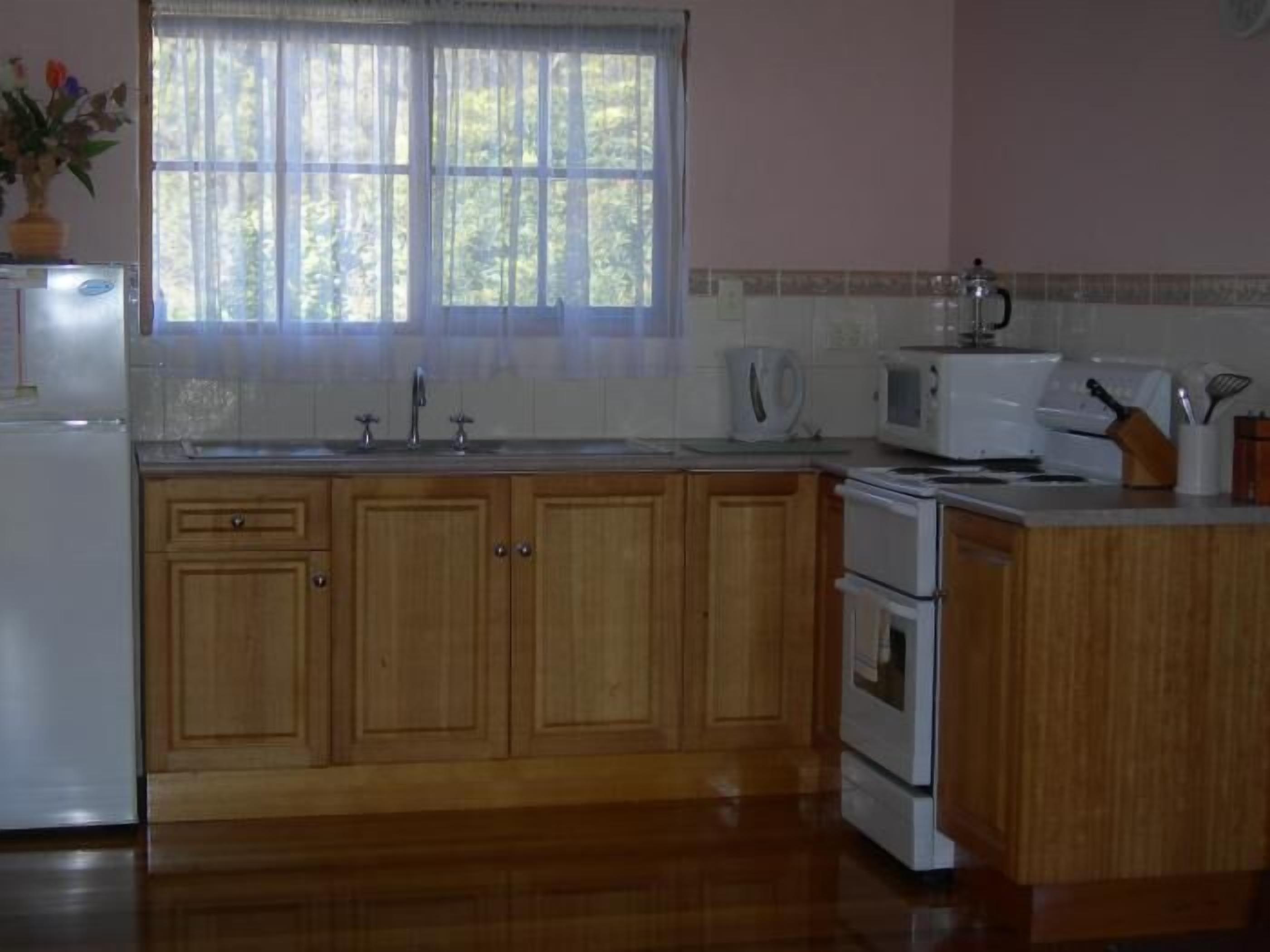 A kitchen with wooden cabinets, a sink, a stove, and a microwave.