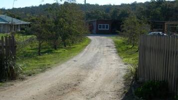 A rural road leading to a house with a red exterior and a white window.