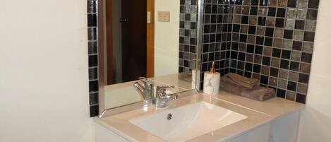 A bathroom with a white sink, a mirror, and a tiled backsplash.
