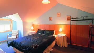 A bedroom with a bed, two bedside tables with lamps, a chair, and a bunk bed against the wall.