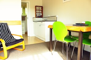 A dining area with a table, chairs, and a kitchen in the background. - Te Awa Motel (Whanganui)