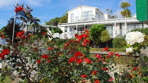 A white building with a balcony, surrounded by red and white flowers. - Te Awa Motel (Whanganui)
