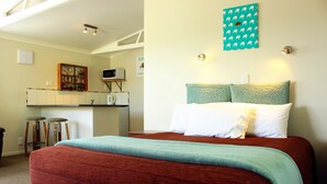 A bedroom with a bed, a desk, and a kitchenette. - Te Awa Motel (Whanganui)