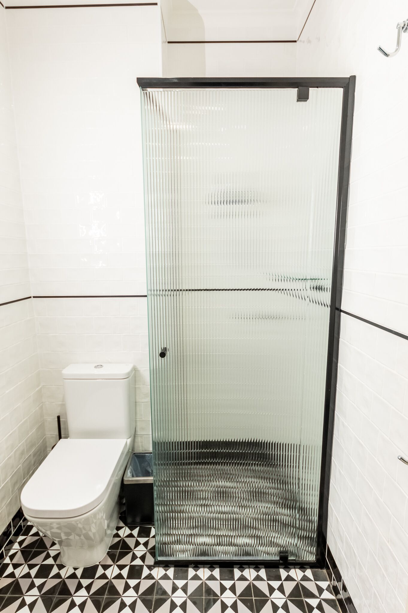 A bathroom with a glass-enclosed shower, a toilet, and a tiled floor.