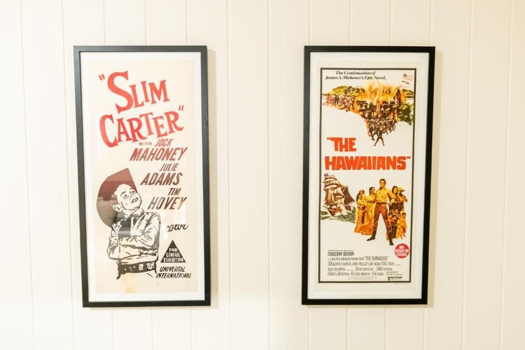 Two framed movie posters, one for 'Slim Carter' and the other for 'The Hawaiians,' mounted on a wall.