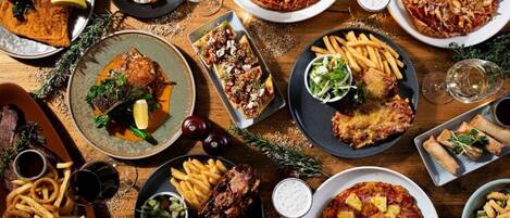A variety of dishes including pizza, steak, and fries, suggesting a restaurant setting.