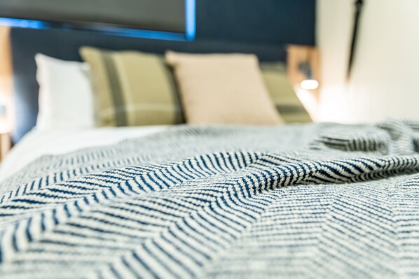 A close-up of a bed with a striped blanket, a headboard, and pillows. - Eyre Hotel Whyalla (Whyalla Playford)