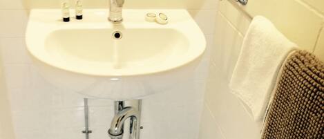 Une salle de bain avec un lavabo blanc, un carrelage noir et blanc au sol et un porte-serviettes sur lequel est posée une serviette marron.