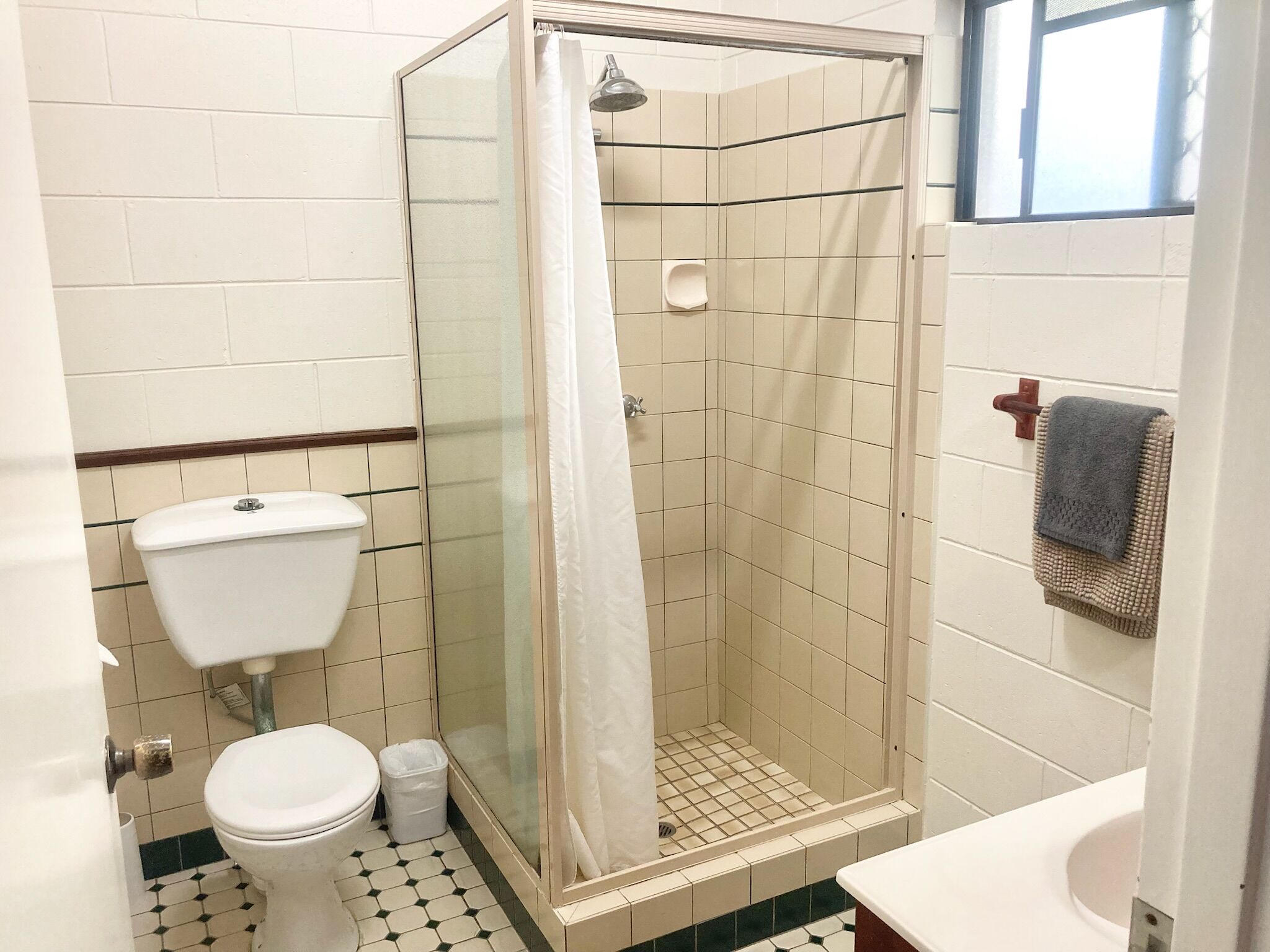 Un baño pequeño con inodoro, ducha con puerta de cristal y lavamanos.