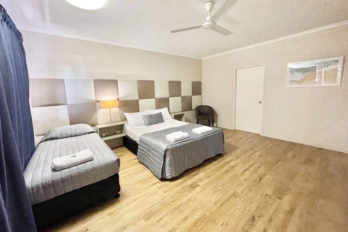 Ein Hotelzimmer mit zwei Betten, einem Deckenventilator und einer Lampe.