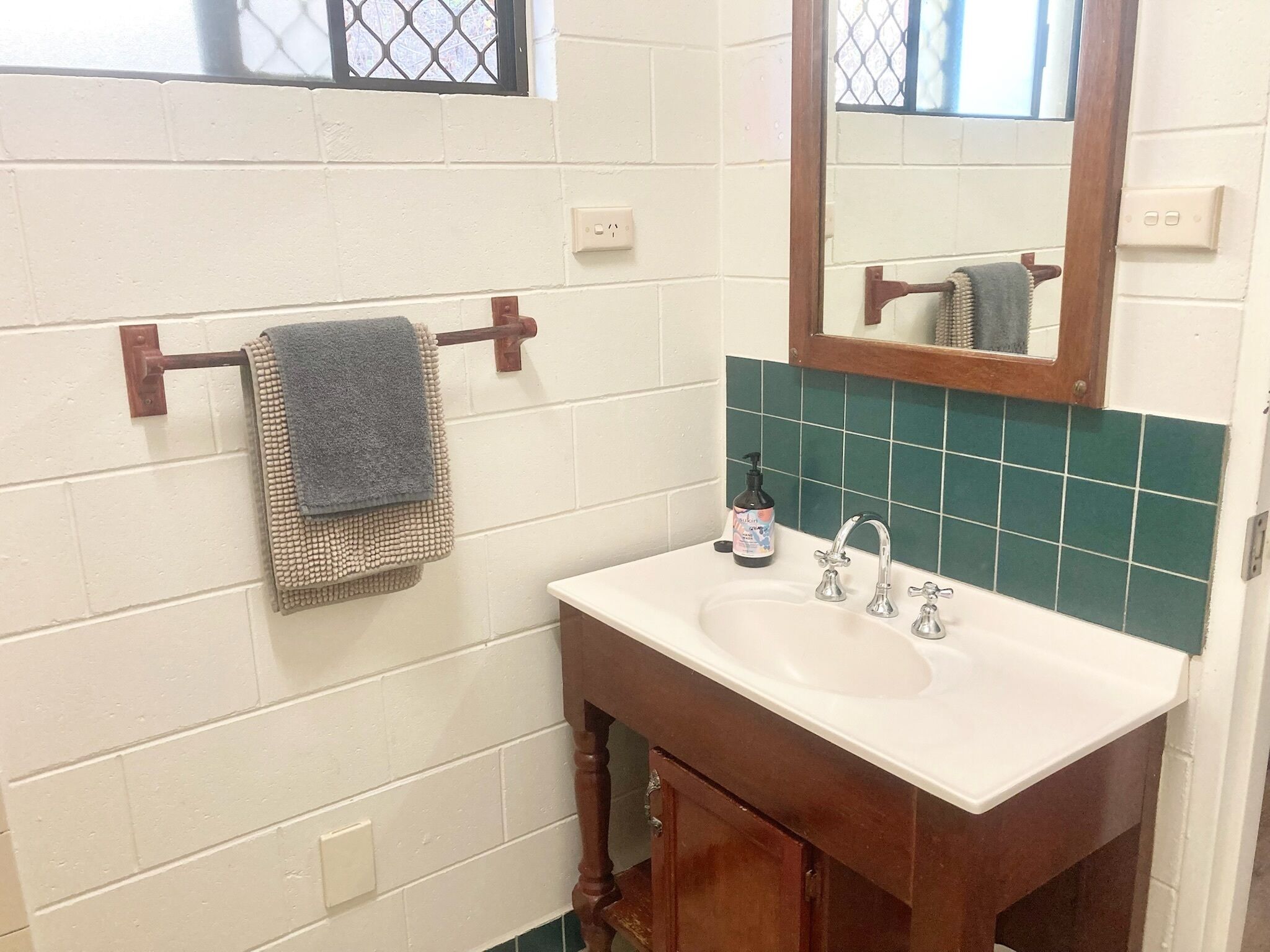 A bathroom with a white sink, wooden cabinet, and a towel rack with a blue towel.