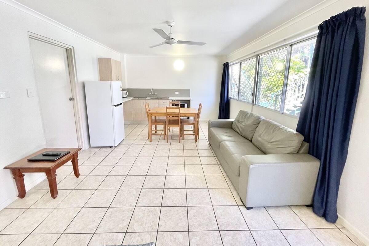 Ein geräumiger Wohnbereich mit Esstisch, einer Couch und einer Küche im Hintergrund.