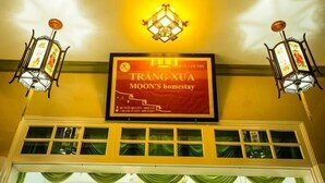 A hotel sign with a red banner and two lantern-style lights on either side. - Moon's Homestay (Da Nang)