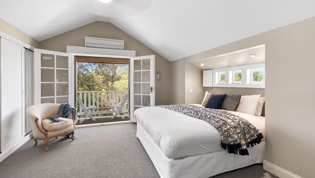 A bedroom with a large bed, a chair, a balcony with a view, and an air conditioning unit. - 65 Main Daylesford - Hepburn Springs (Hepburn Springs)