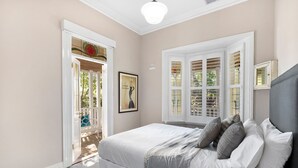 A bedroom with a bed, a window with shutters, and a door leading to an outdoor area. - 65 Main Daylesford - Hepburn Springs (Hepburn Springs)