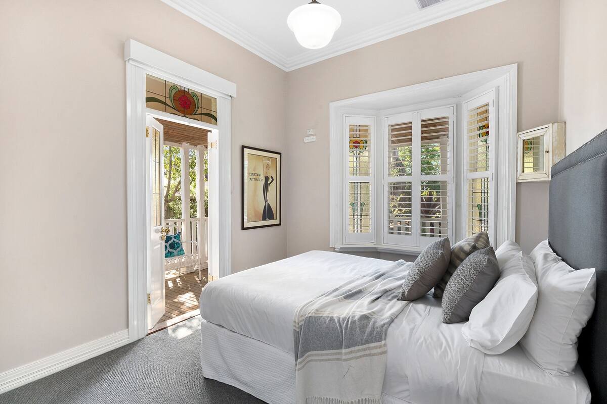 Un dormitorio con cama, una ventana con contraventanas y una puerta que da a un espacio exterior.