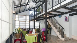 A dining area with tables, chairs, and decorative elements like flowers and wall art. - Agga Youth Hotel (Yangon)