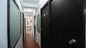 A hallway with wooden flooring, black doors, and a tiled wall. - Agga Youth Hotel (Yangon)