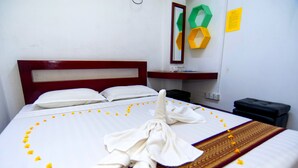 A neatly made bed with a towel and flower petals arranged on the bedspread. - Agga Youth Hotel (Yangon)
