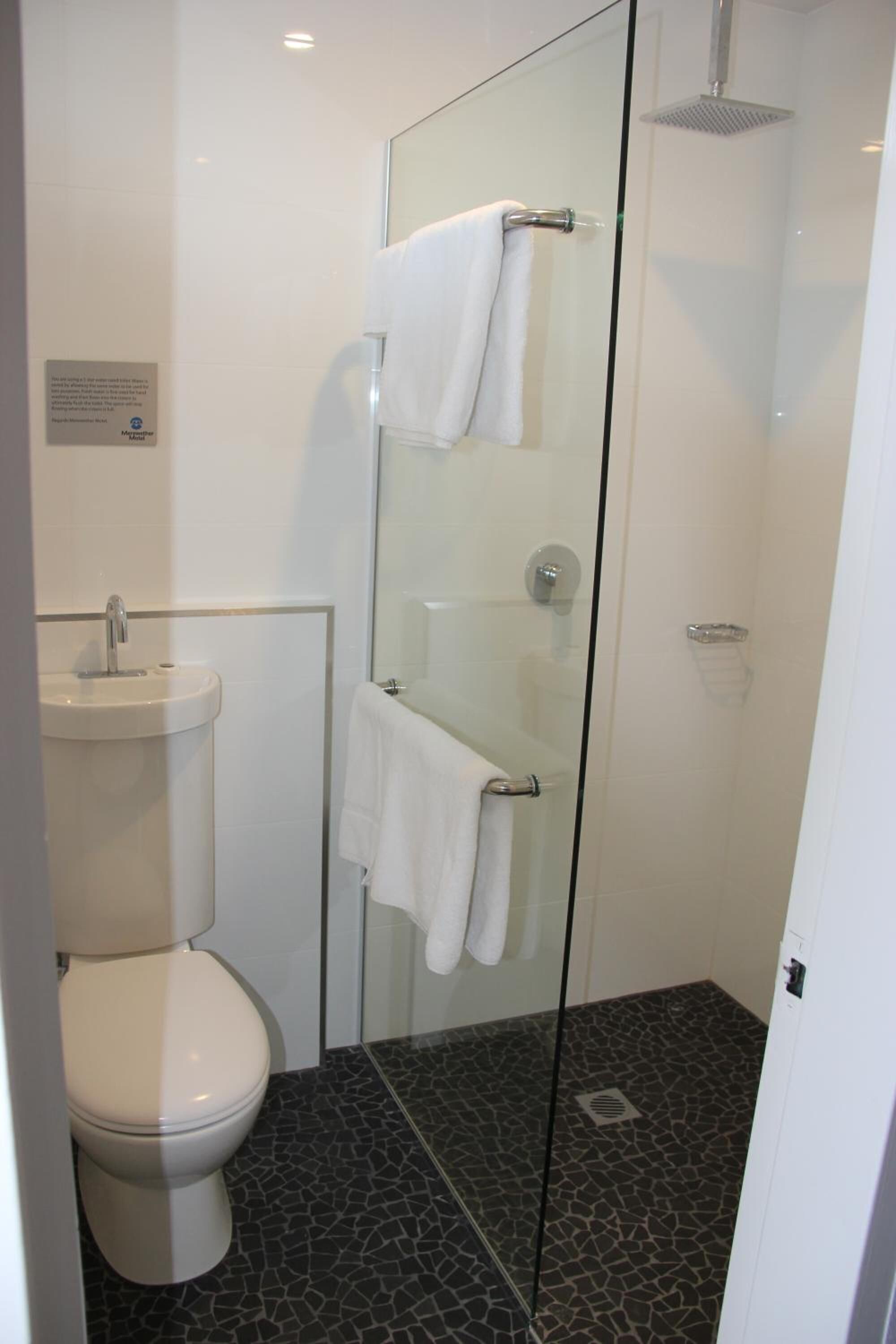 A modern bathroom with a glass-enclosed shower, a white toilet, and a sink.