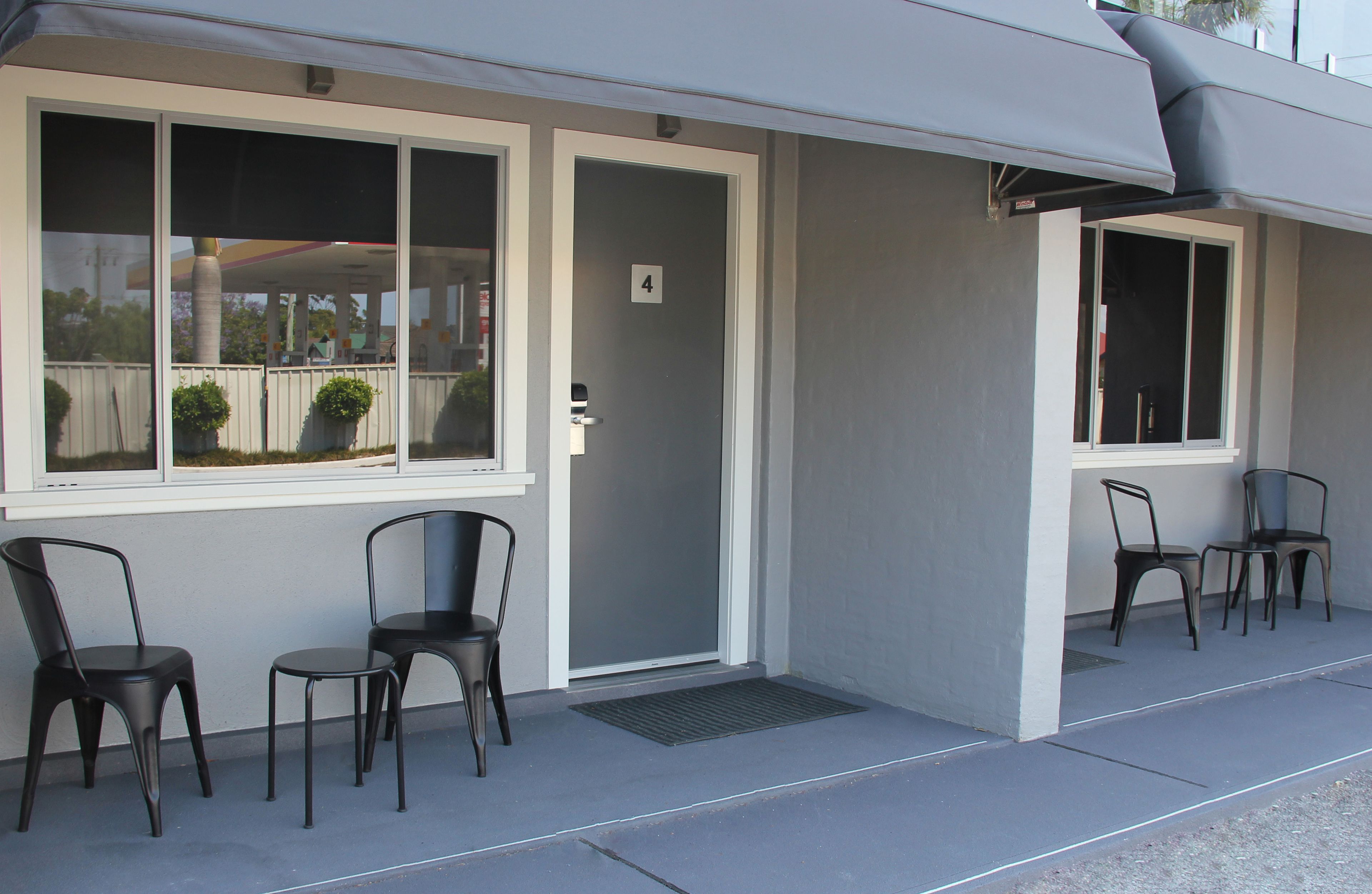A building with a covered outdoor seating area, a door marked with the number 4, and two windows.