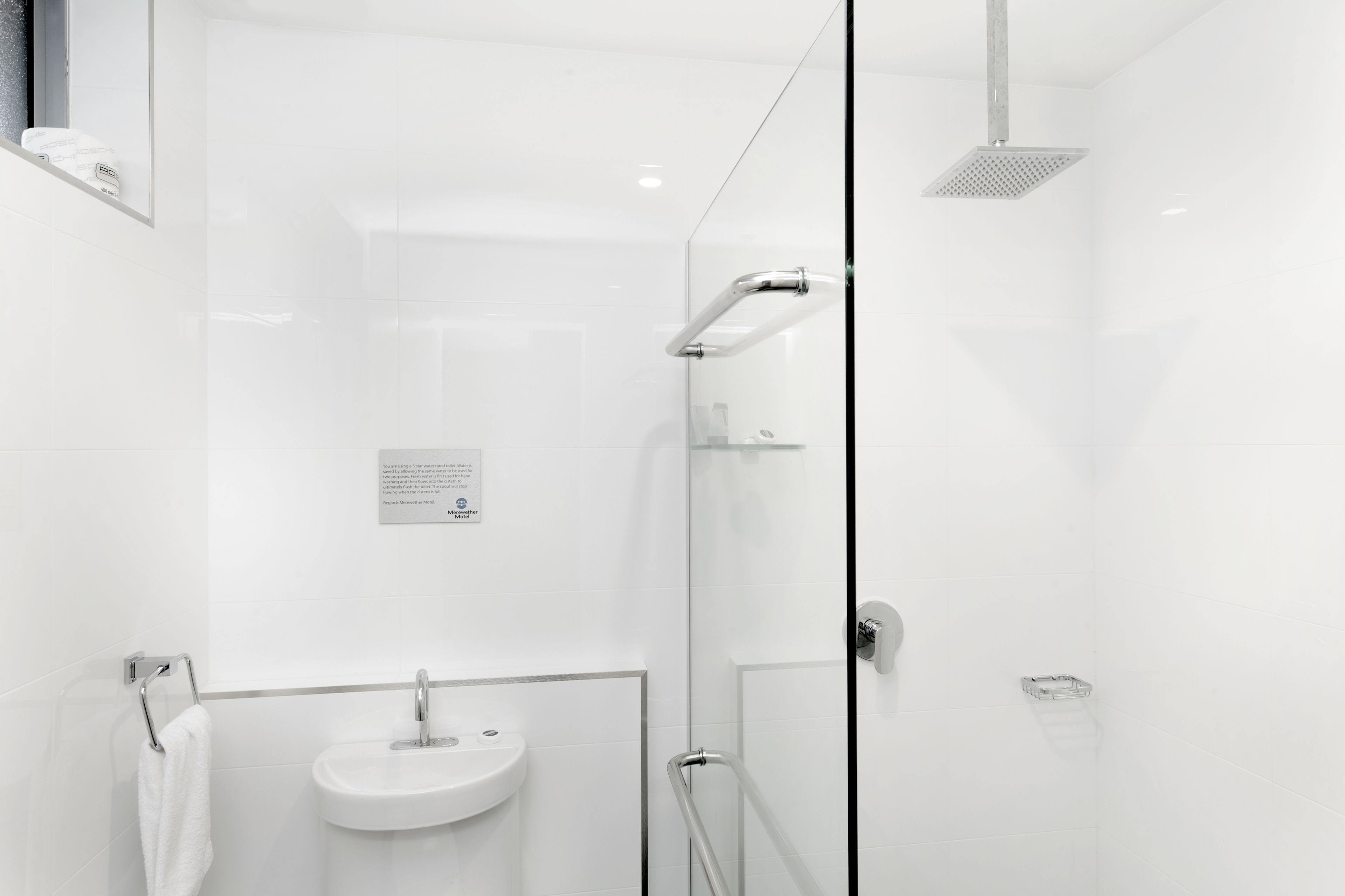 Un baño moderno con cabina de ducha de vidrio, un lavabo y un perchero para toallas.