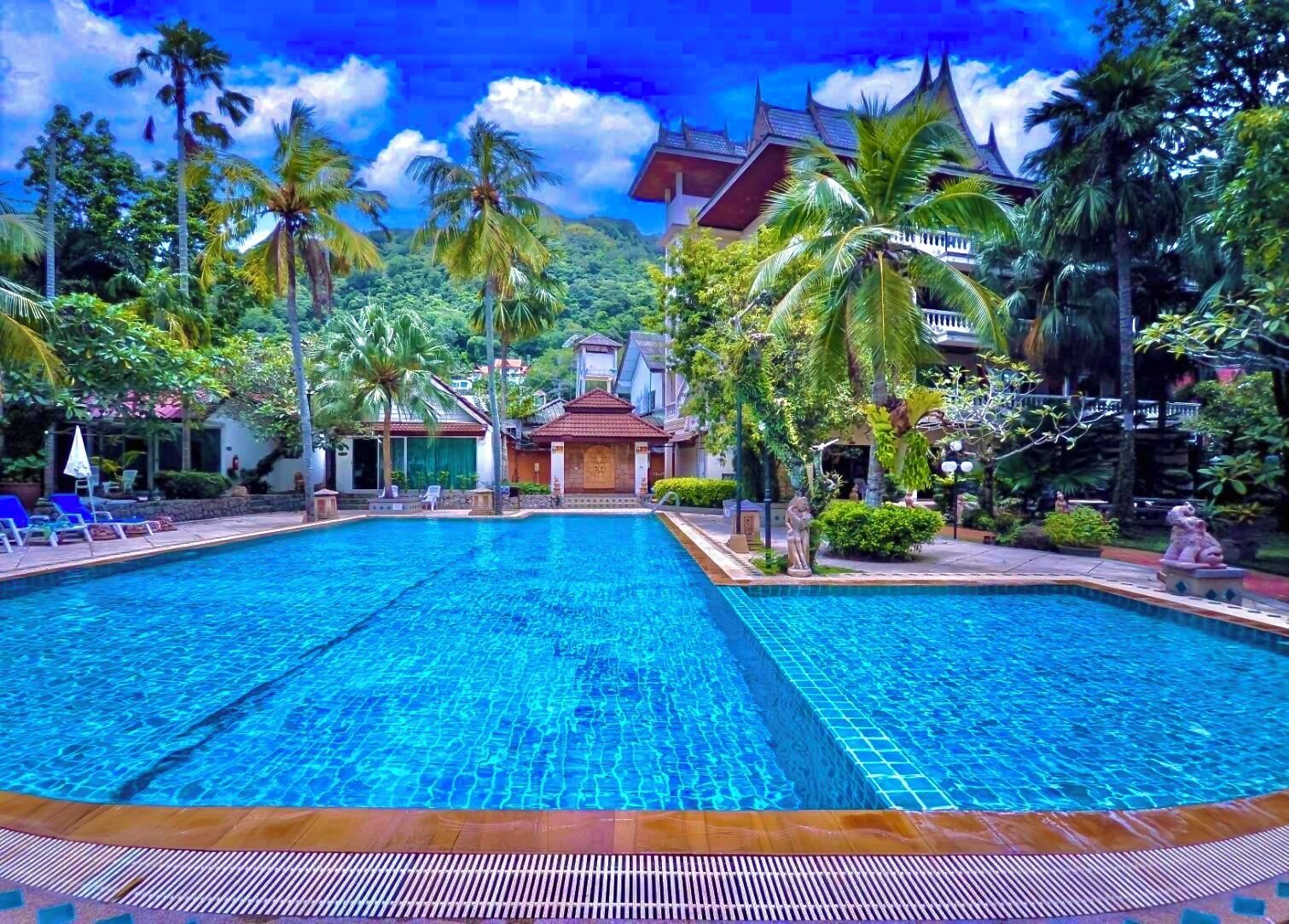 A swimming pool with lounge chairs and palm trees.