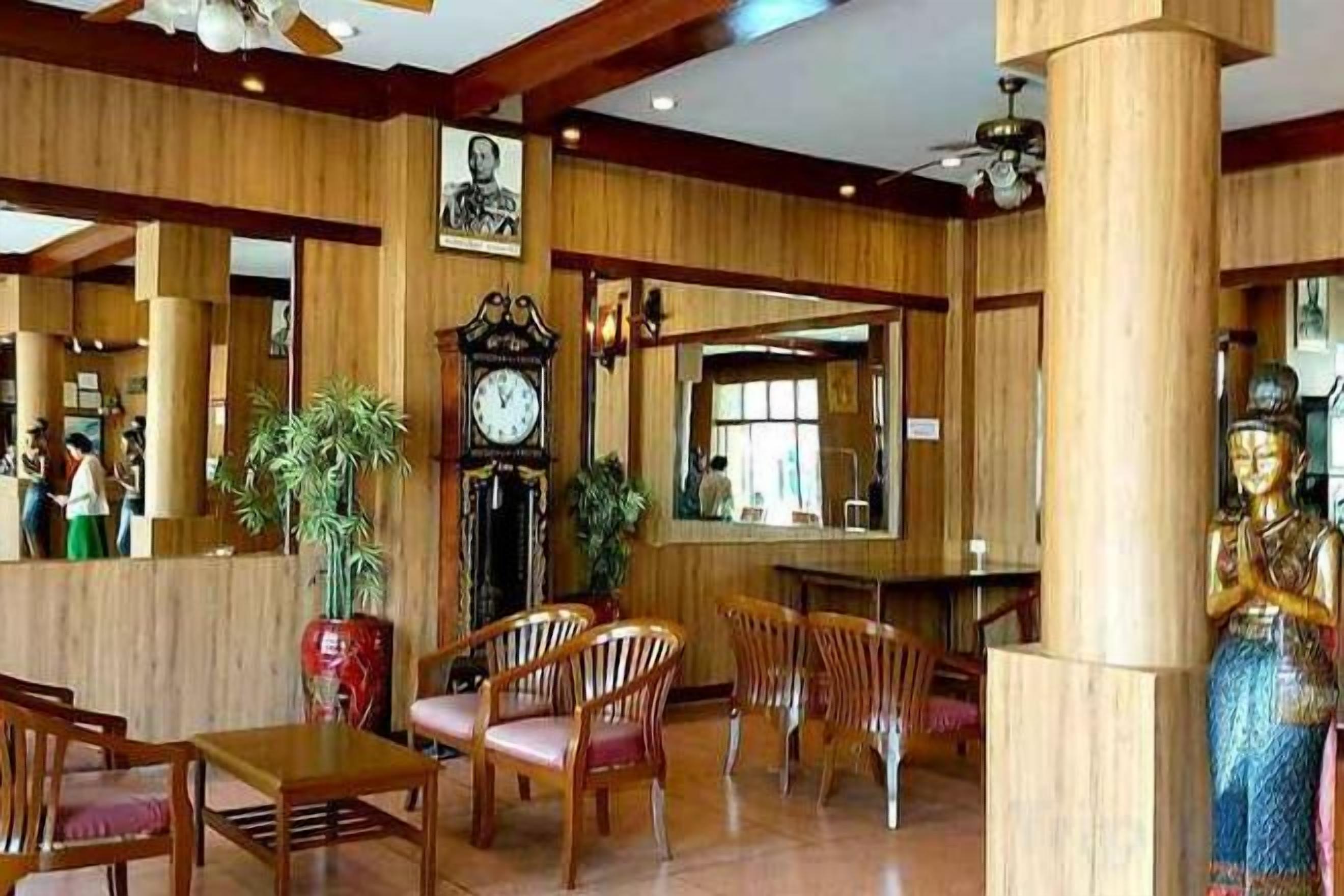 A hotel lobby with wooden paneling, a large clock, and a Buddha statue.