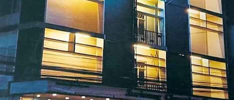 A hotel with multiple floors, illuminated windows, and a sign indicating it is a hotel.