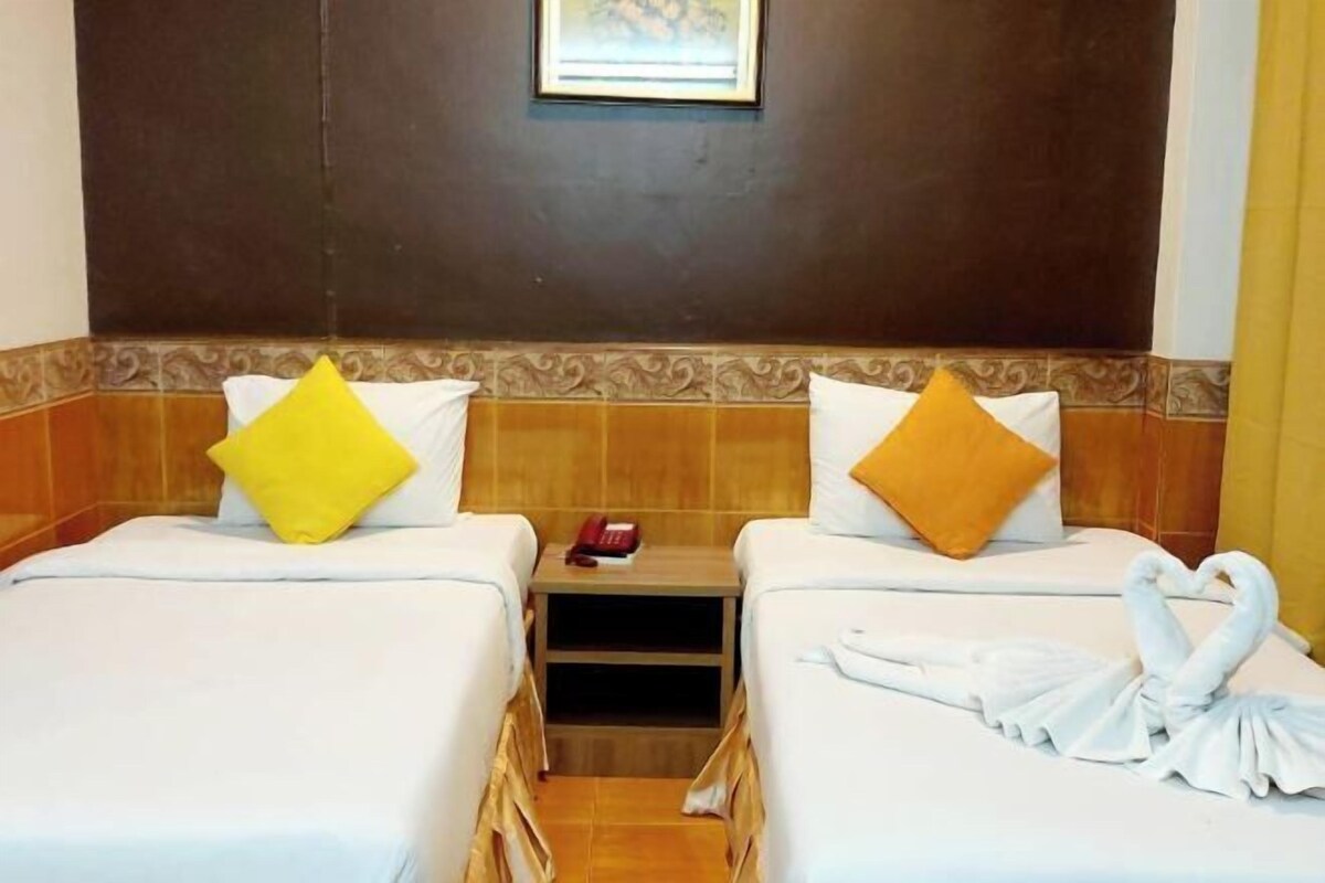A hotel room with two beds, a wooden headboard, a small window, and a towel art decoration.