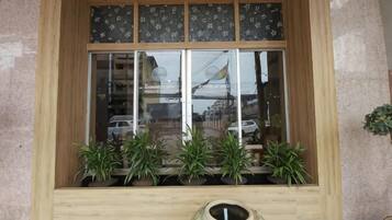 Una ventana con marco de madera, varias plantas en macetas y un florero.