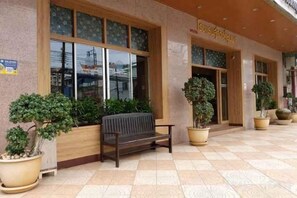 A hotel entrance with a wooden bench, potted plants, and a tiled floor. - Suriwong Chumphon Hotel (Chumphon)